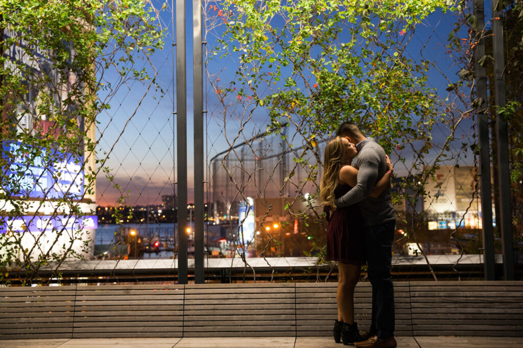 night time photo of couple embracing standing on a bench on the Highline NYC