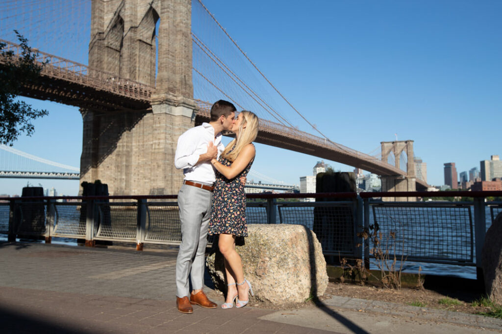 color photo of couple kissing by the Brooklyn Bridge nyc