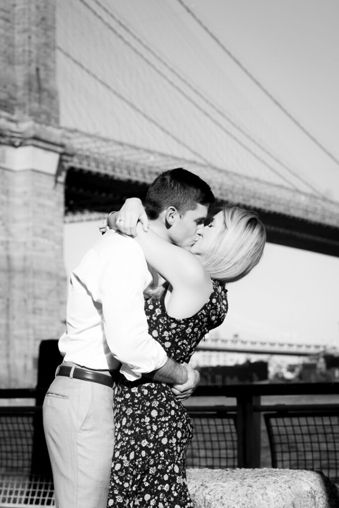 black and white photo of couple kissing by the brooklyn bridge nyc