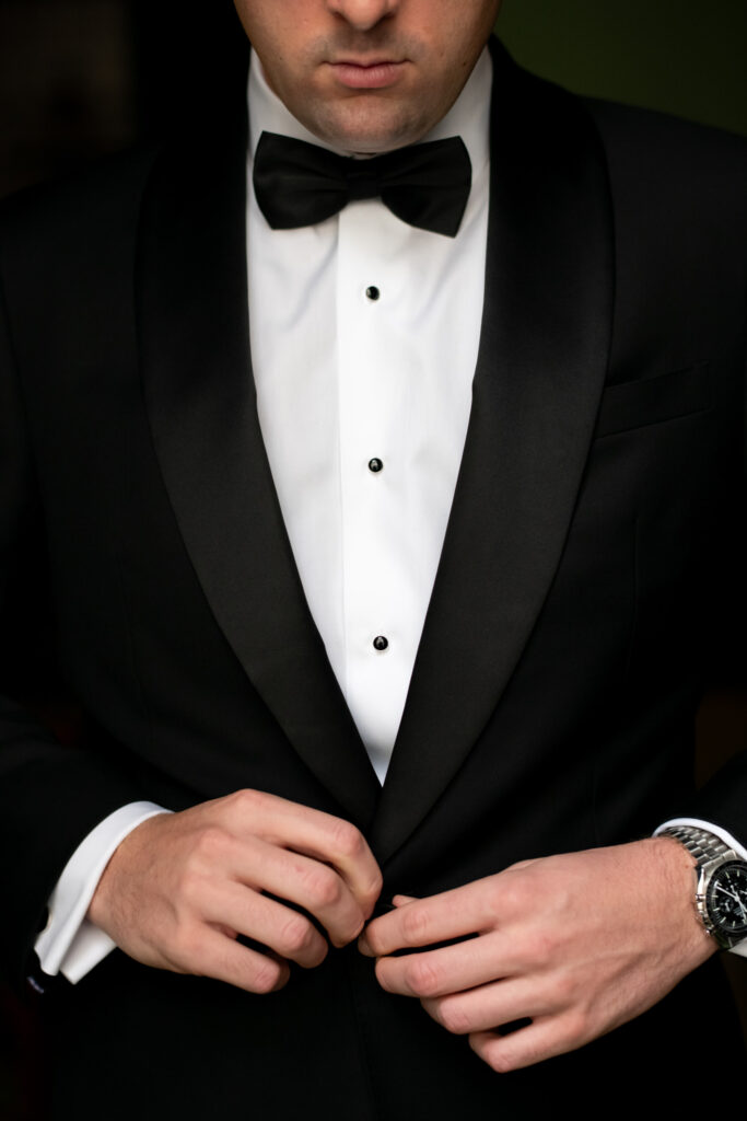 detail of groom buttoning jacket