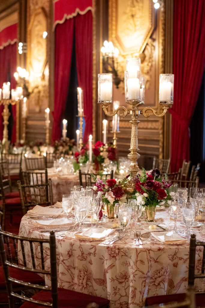 nyc reception table with deep reds and candles lit everywhere 