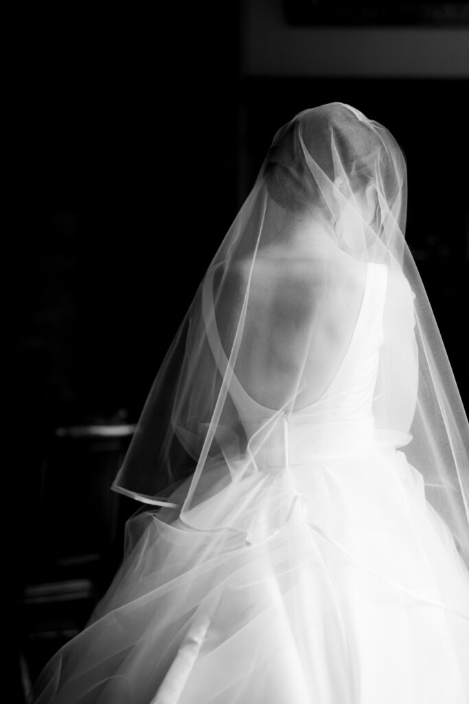 back of bride in veil half length portrait in black and whtie